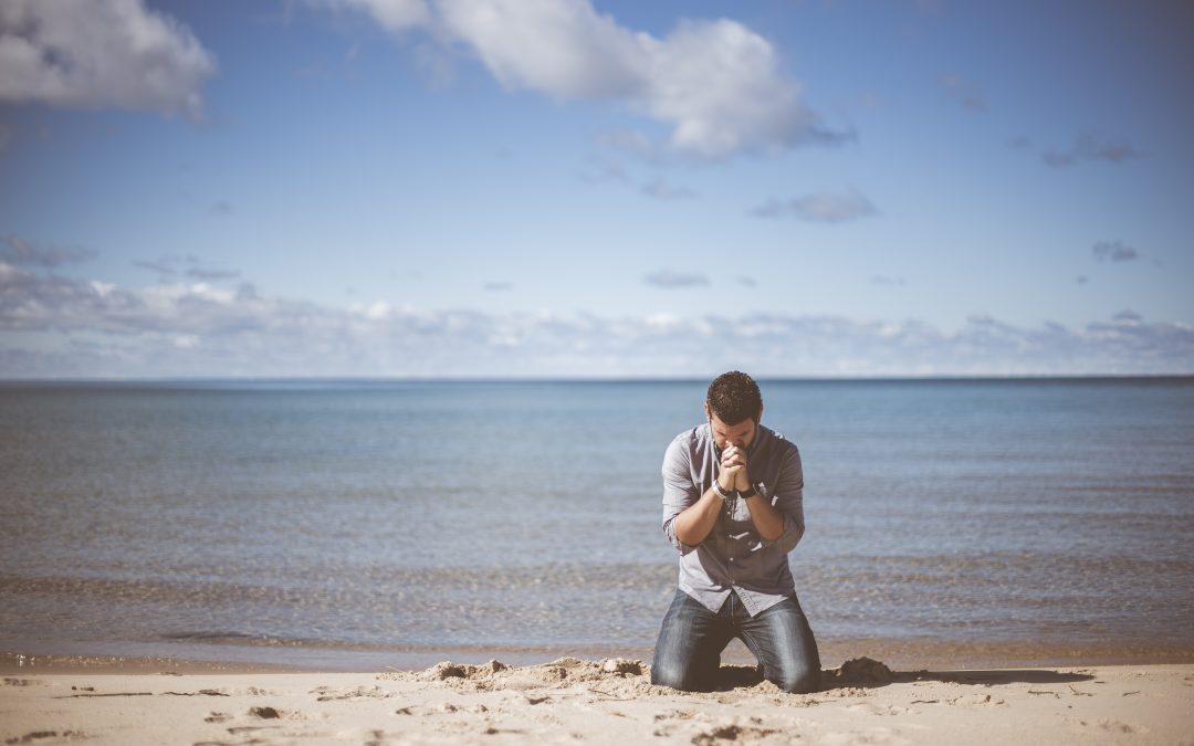 man praying on the beach